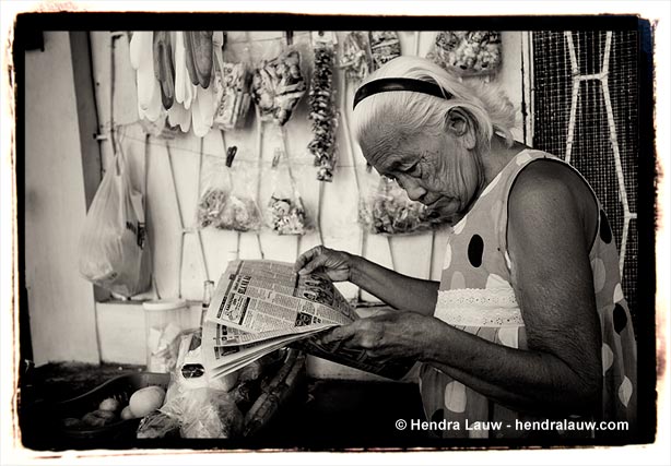 An old woman reading newspaper at the Manila North Cemetery