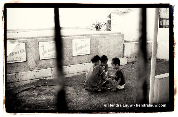 Three boys playing at Manila North Cemetery